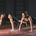Sportswoman and sportsman doing push ups in gym in sports hall