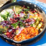 Shaksouka Hola Mexico. Eggs baked in aromatic tomato and peppers paste, with beans, served with marinated cactus, guacamole, salsa verde, salsa chipotle, cheddar and tortillas