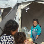 CH11267189-Amal--sits-in-the-entrance-of-their-family-tent--2