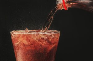 pour cola from the bottle to glass and bubble soda on black background