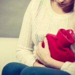 Woman feeling stomach cramps sitting on cofa