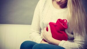 Woman feeling stomach cramps sitting on cofa
