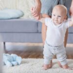 Cute baby walks with assistance at home