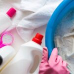 Housewife with rubber protective gloves washing clothes with different detergents in the bowl. Dry cleaning concept. Clothes care. Chores of maid. Regular washing.
