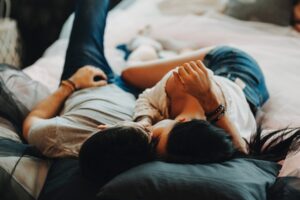 Attractive romantic couple laying on bed ,hugging and kissing in a cozy room.